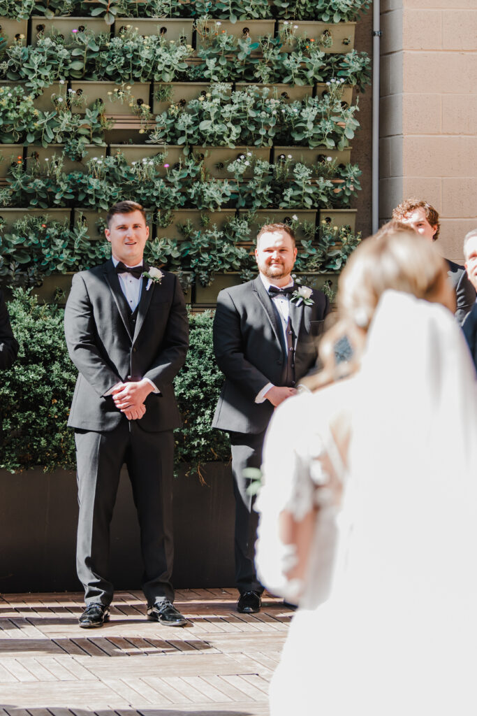 groom looks toward the bride walking down the aisle
